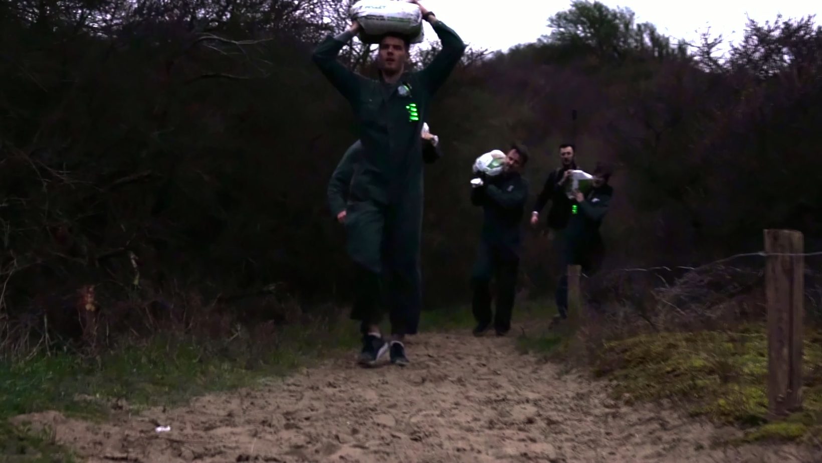 Team loopt met zandzakken door de duinen tijdens Boundary Beach Bootcamp