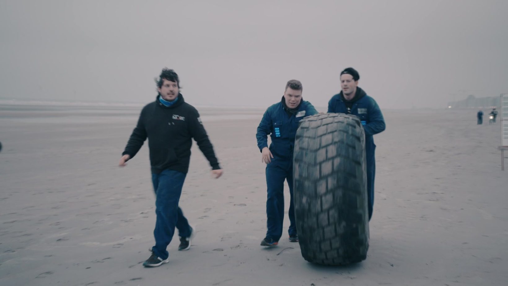 Team duwt een zware band over het strand tijdens Boundary Beach Bootcamp