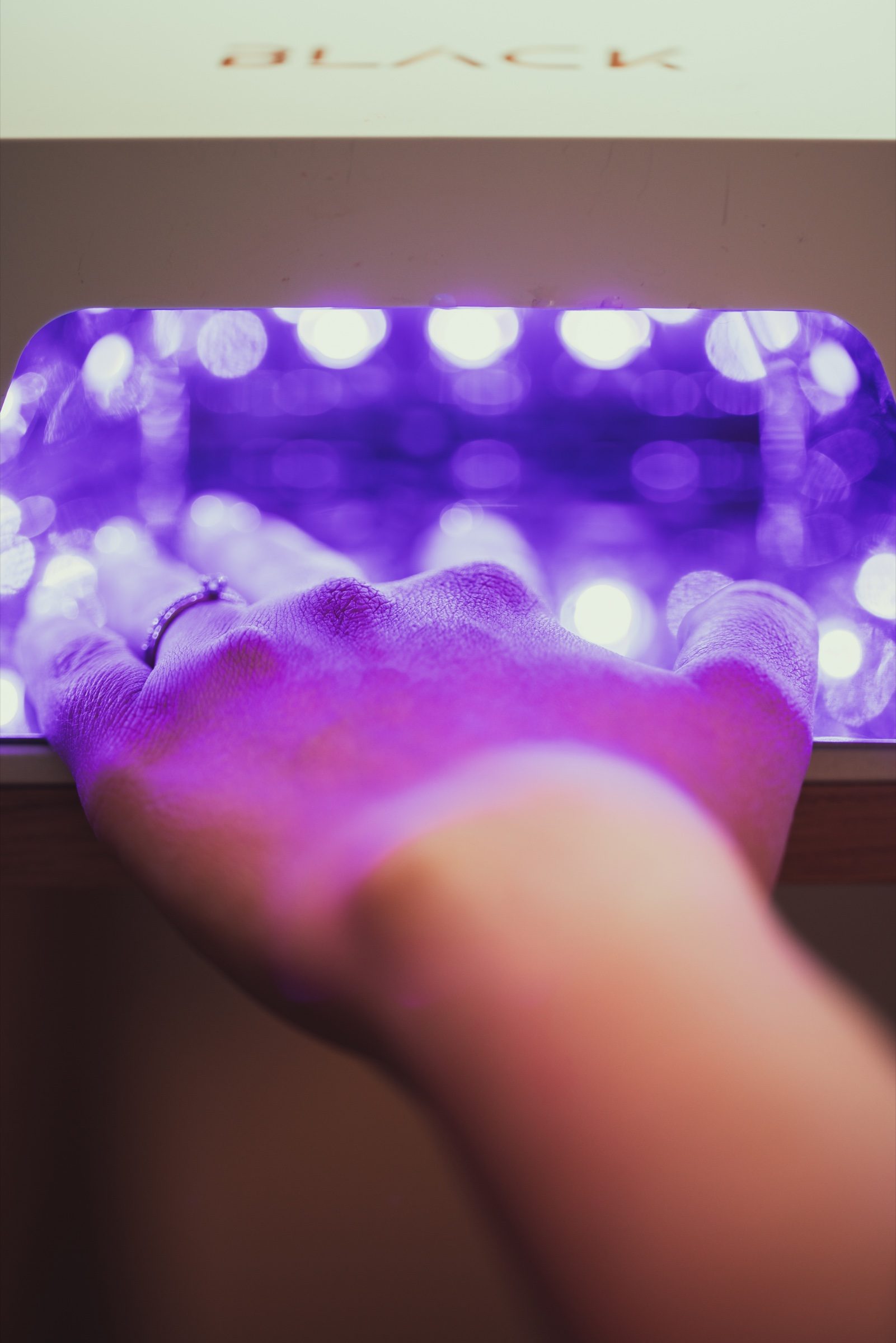 Hand onder paars licht tijdens een behandeling bij By Charlotte