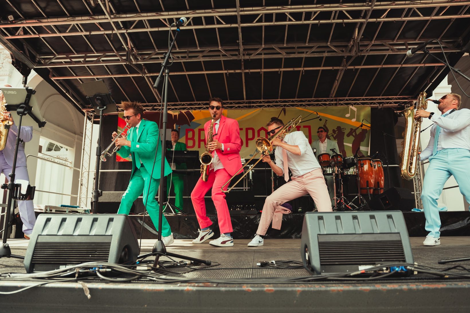 Muzikanten van LAIF in kleurrijke kostuums op het podium van Brasspartij