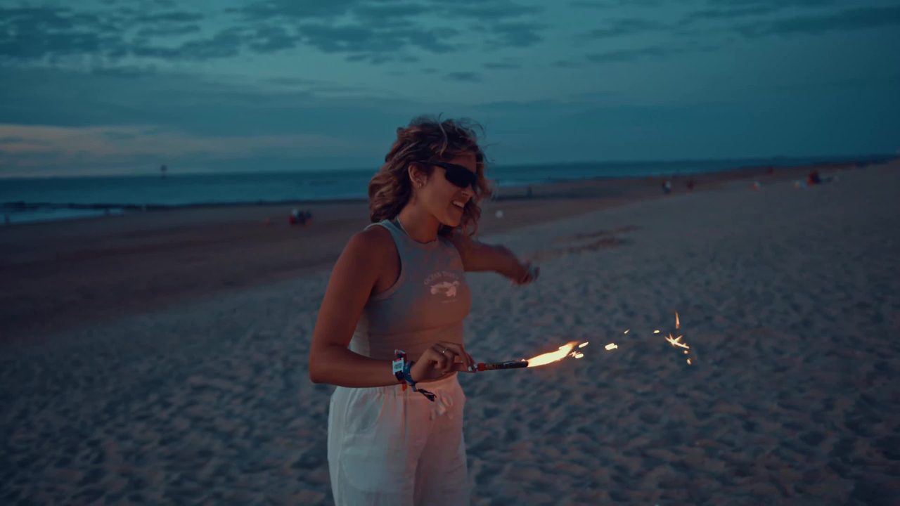 Filmbeeld van een vrouw met vuurwerk op het strand voor WeDream